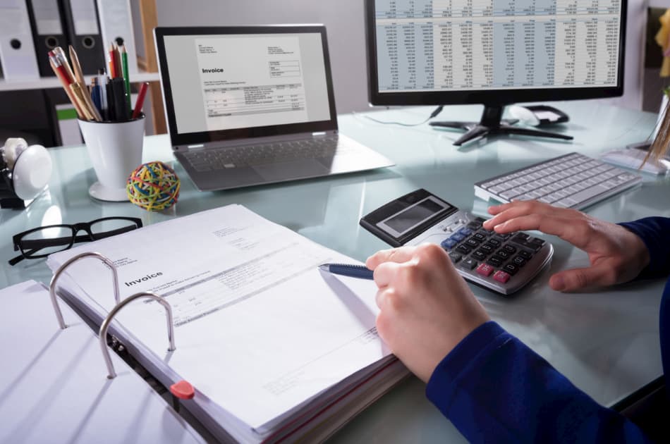 Person calculating finances at office desk.